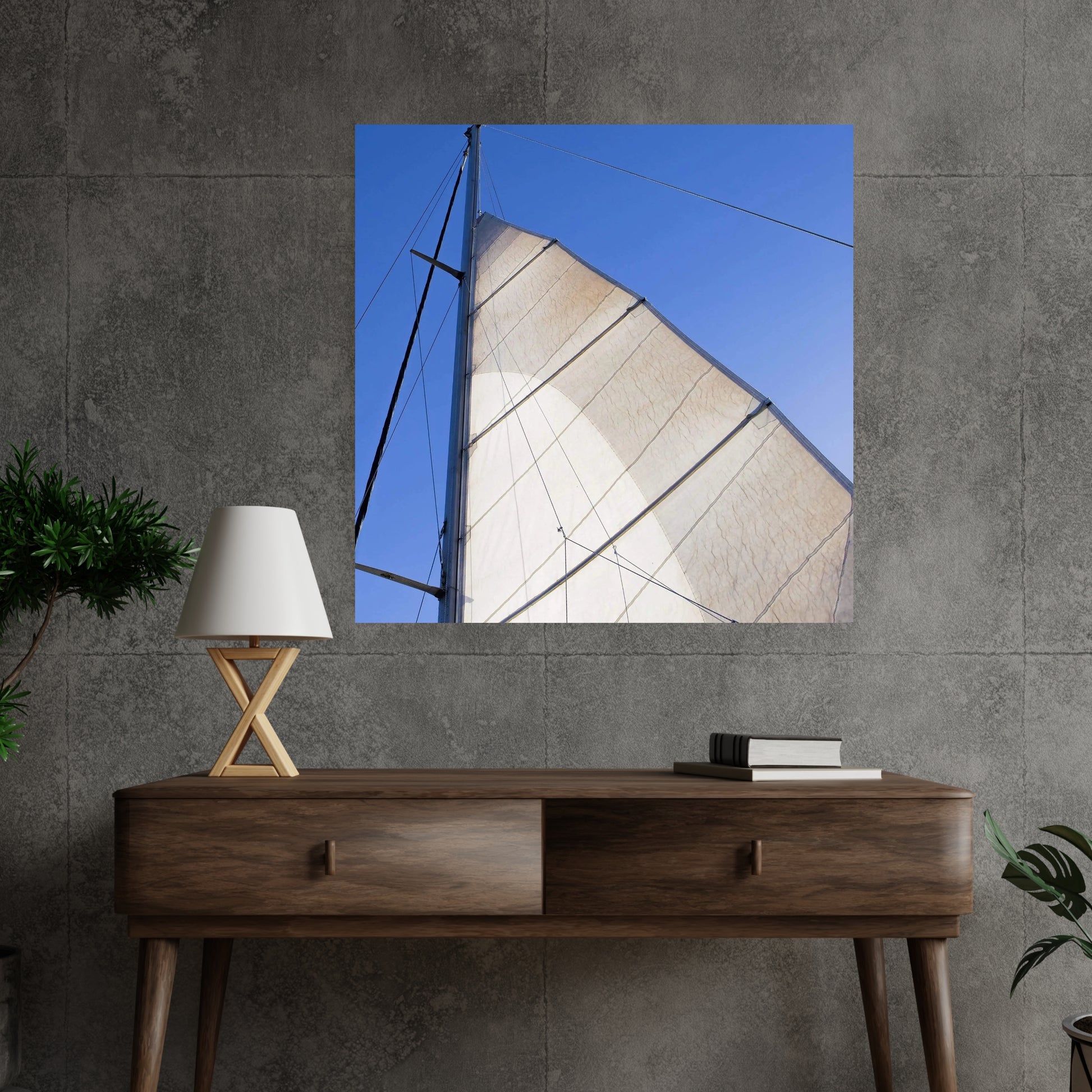 large acrylic art of a sailboat mast looking upward and hanging on a dark concrete wall above a brown entryway table