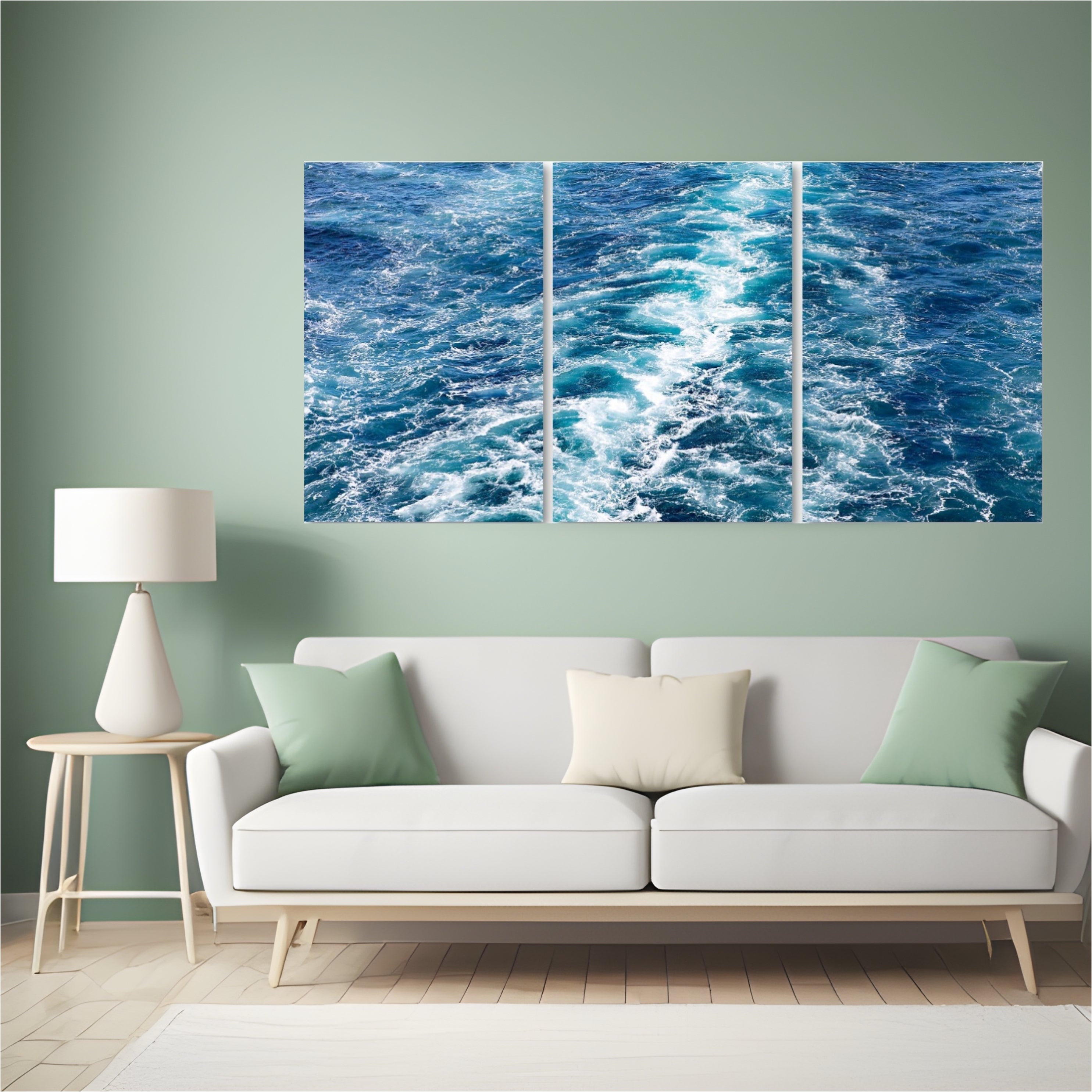 Large triptych blue ocean wall art displayed in a coastal-inspired living room with white sofa