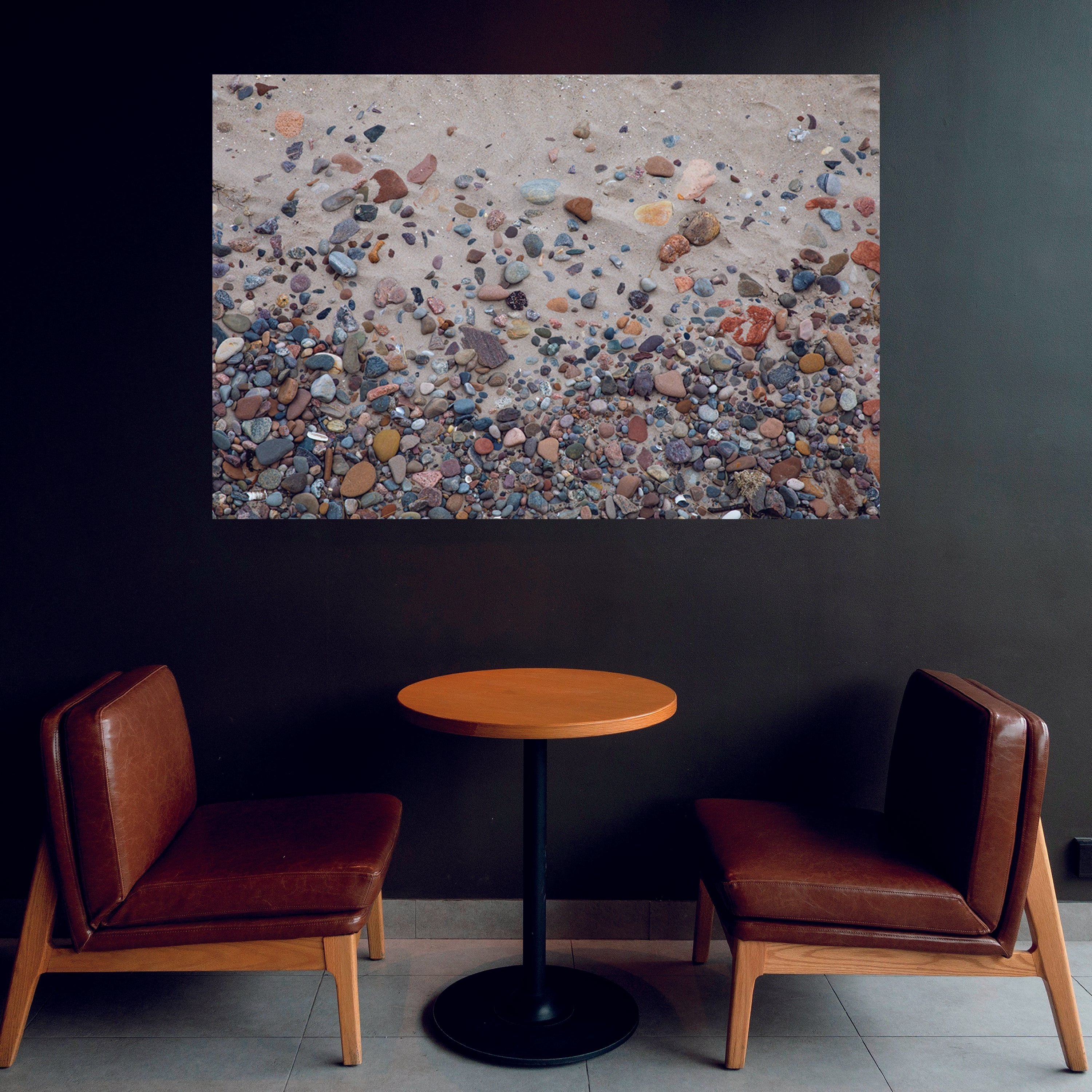 Casual sitting area with dark wall highlighting a fine art wall decor of Nairn Beach Scotland with colorful rocks throughout the sand. Art by Lisa Blount Photography
