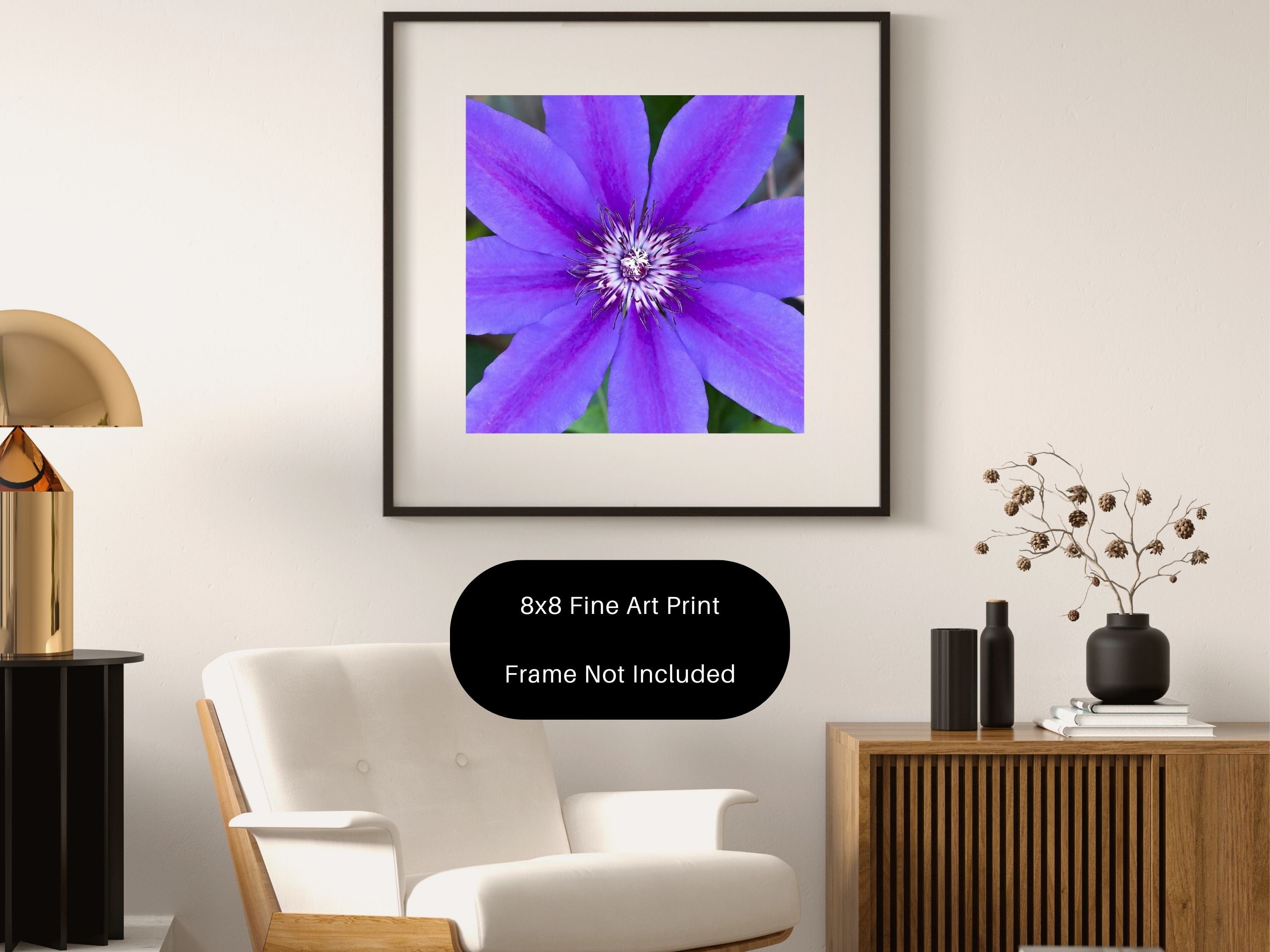 Framed purple clematis flower print on a wall with decorative items in a room.
