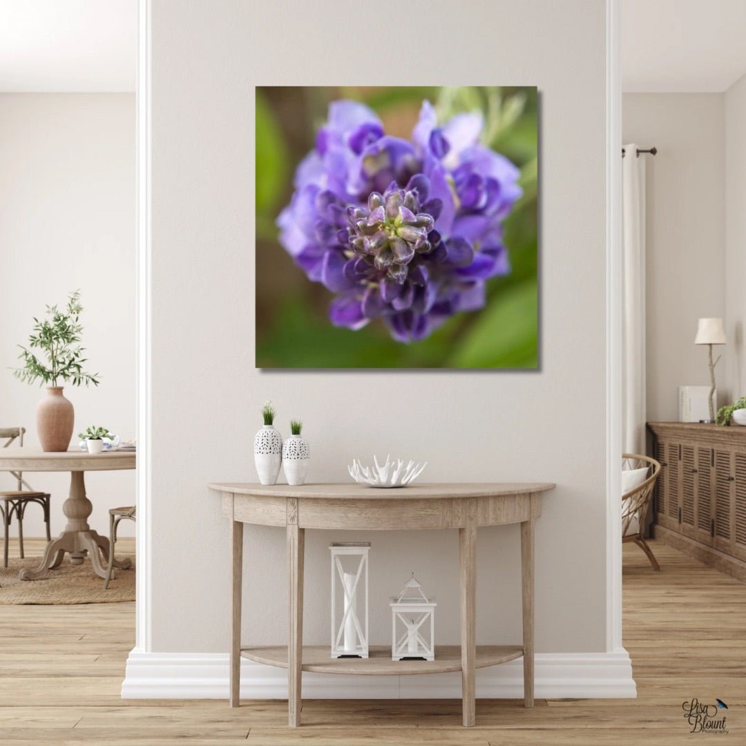 Purple wisteria flower modern photography on a wall above a wooden console table in a room.