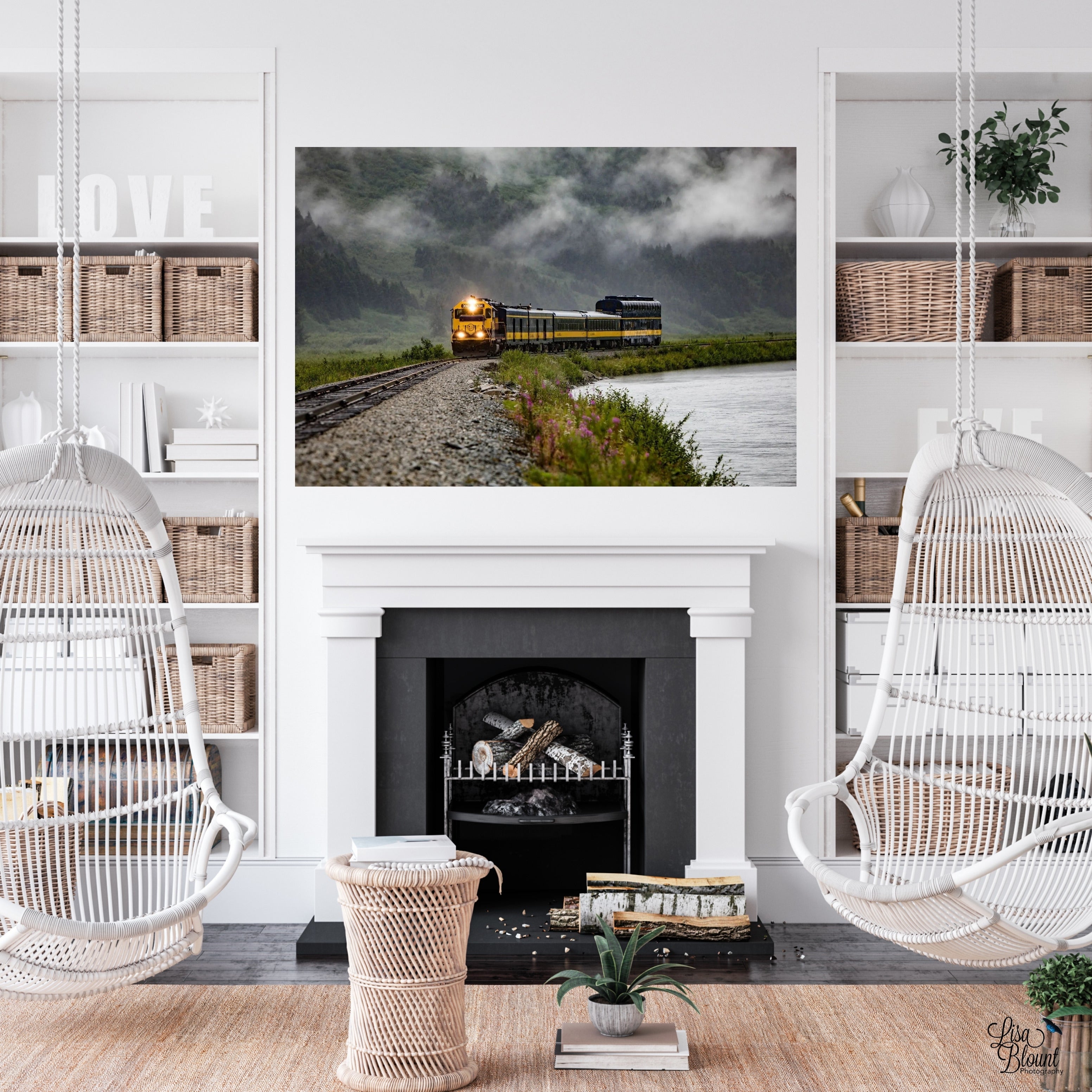 Aboard Alaska train wall art displayed above a fireplace in a bright white boho-style living room with hanging wicker chairs.