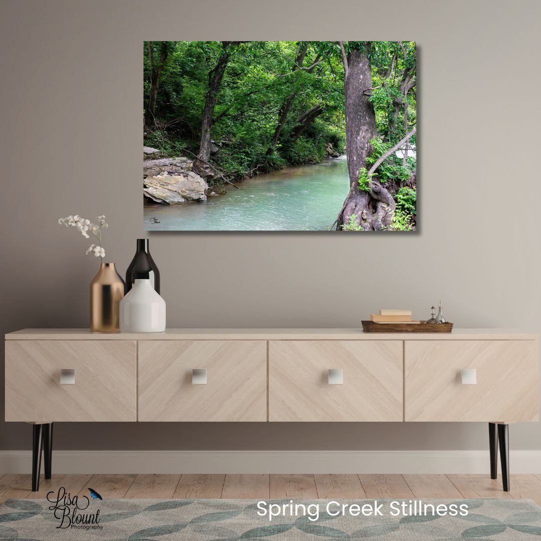 Spring Creek Stillness Arkansas creek wall art displayed above a neutral modern console table with soft green water and woodland tones.
