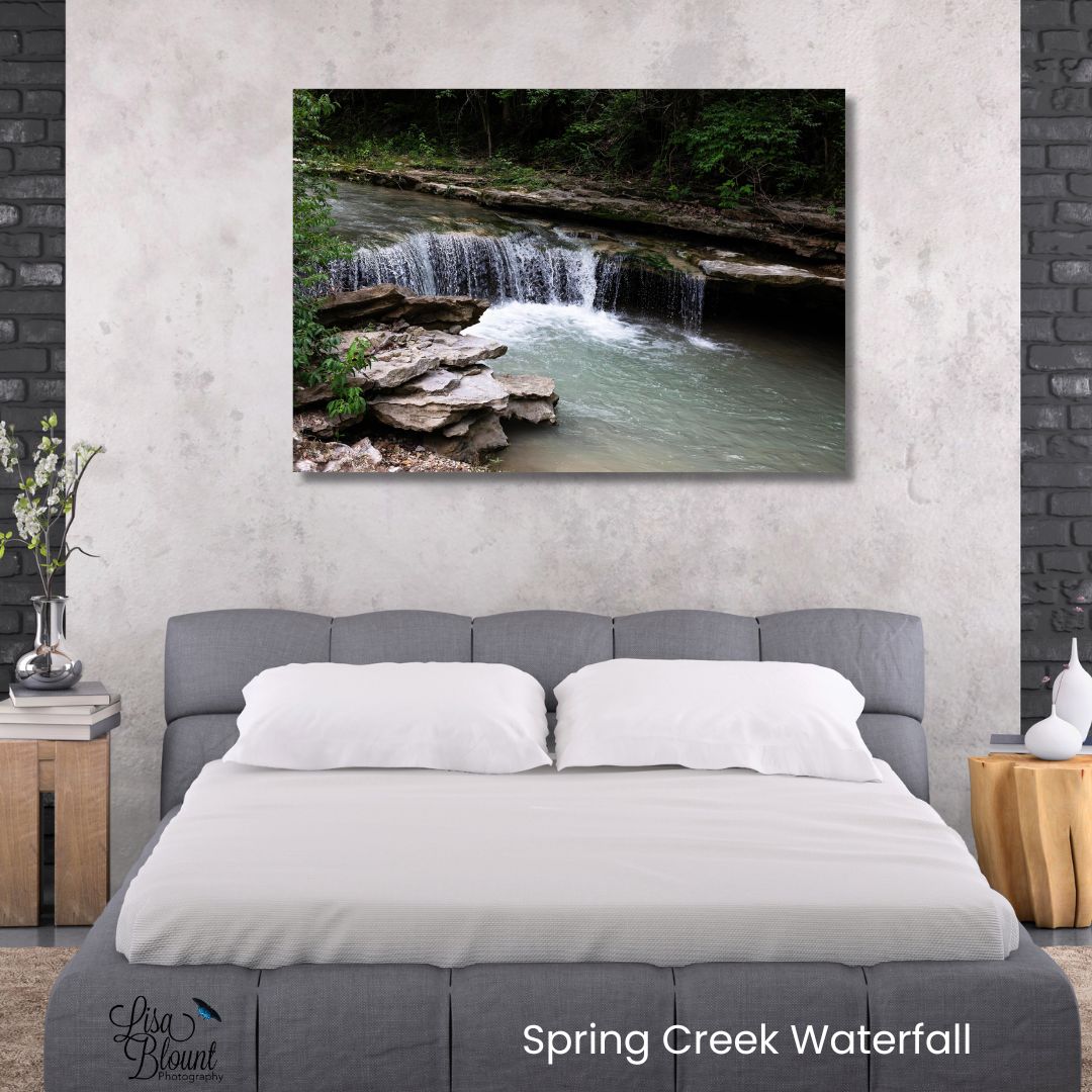 Arkansas waterfall wall art displayed above a bed featuring Spring Creek Waterfall with layered rock, moving water, and peaceful woodland greens.