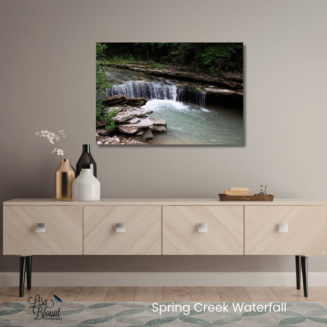 Spring Creek Waterfall Arkansas waterfall wall art displayed above a neutral modern table with natural decor and calming woodland tones.