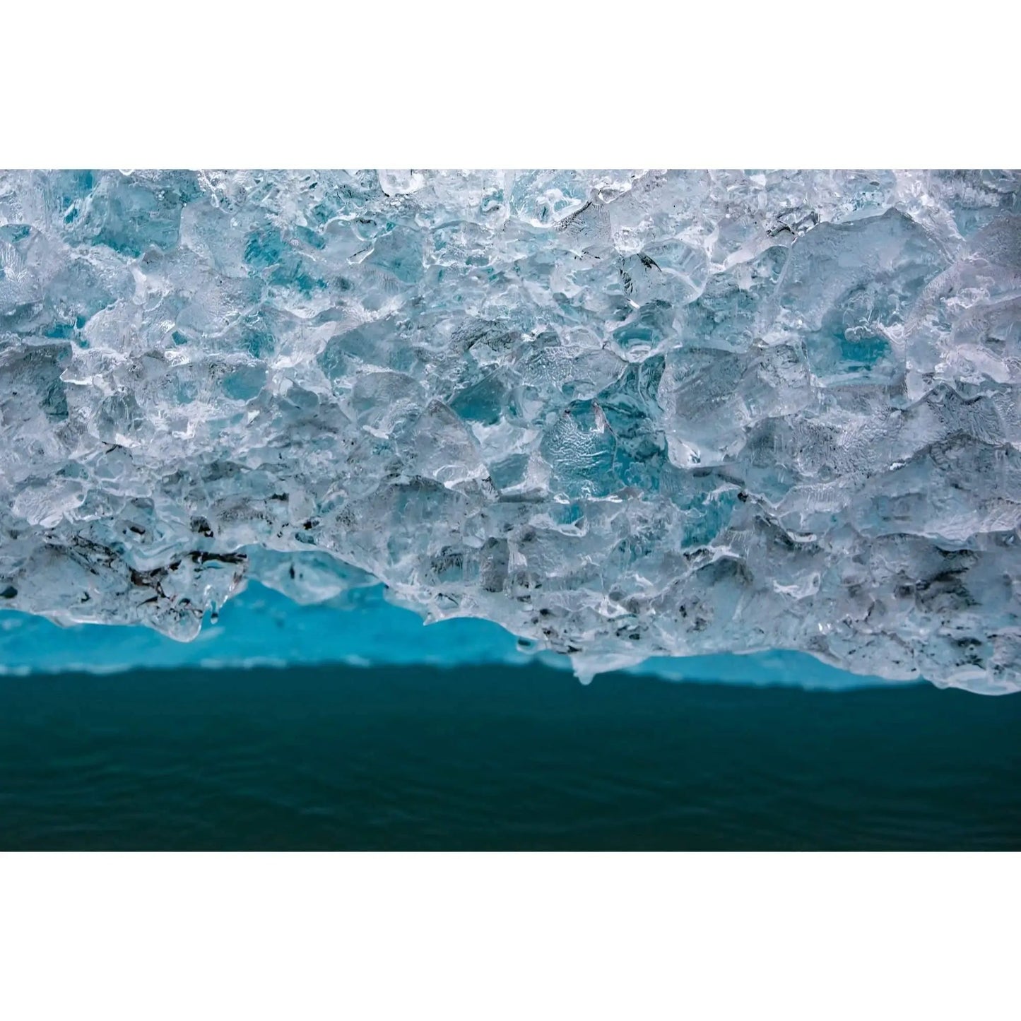Elongated art of cold iceberg in spencer lake Alaska featuring detailed ice crystals and teal water