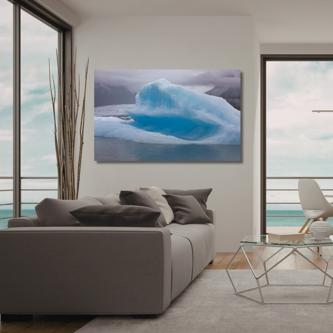A TruLife Acrylic wall art print depicting a vibrant blue glacier in icy waters at Spencer Lake, displayed in a modern living room setting above a gray sofa.