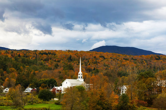 Stowe Vermont white church in the fall with bright orange leaves on the mountains and dark clouds above.  Canvas is 30x20 and can be custom sized on request.