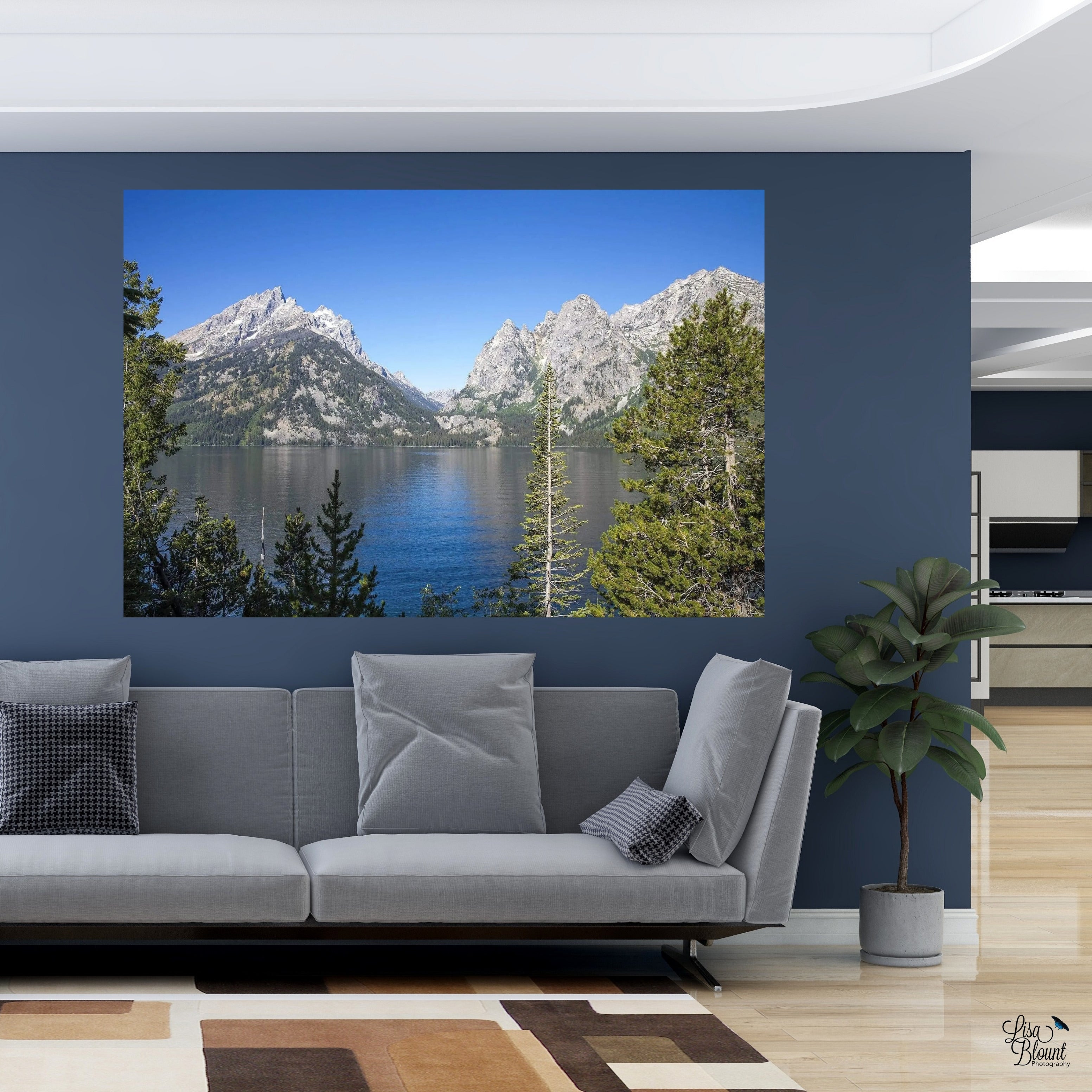 Jenny Lake fine art photography displayed in a modern living room with a blue accent wall and gray sofa.