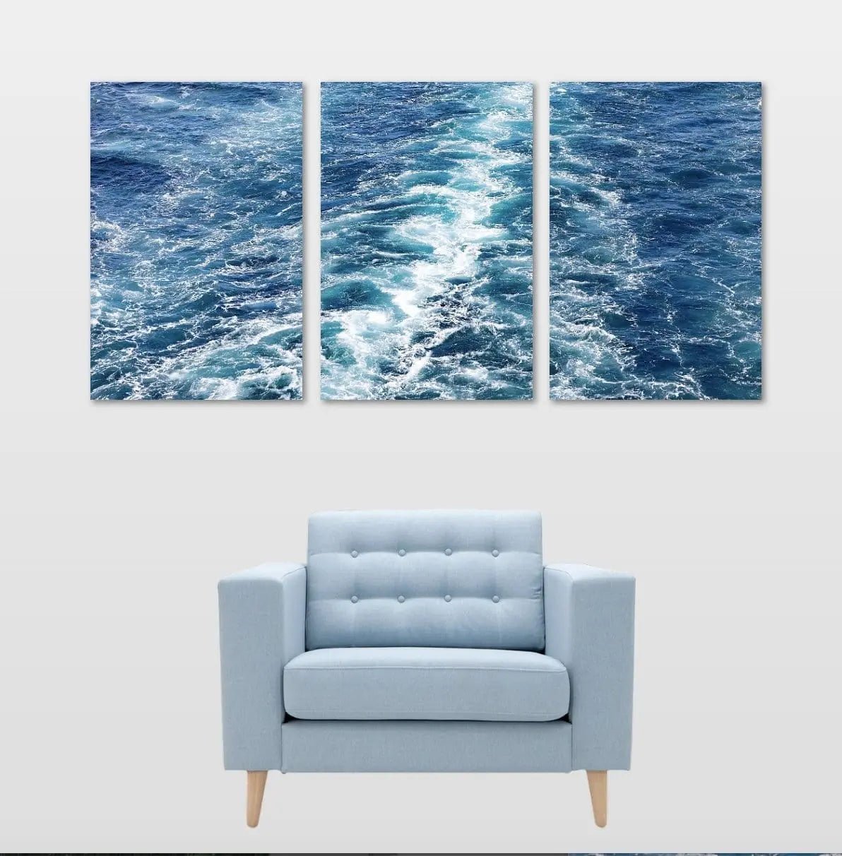 Three-panel abstract ocean wave artwork in soft blues and teals, styled above a modern chair for a coastal-inspired interior.