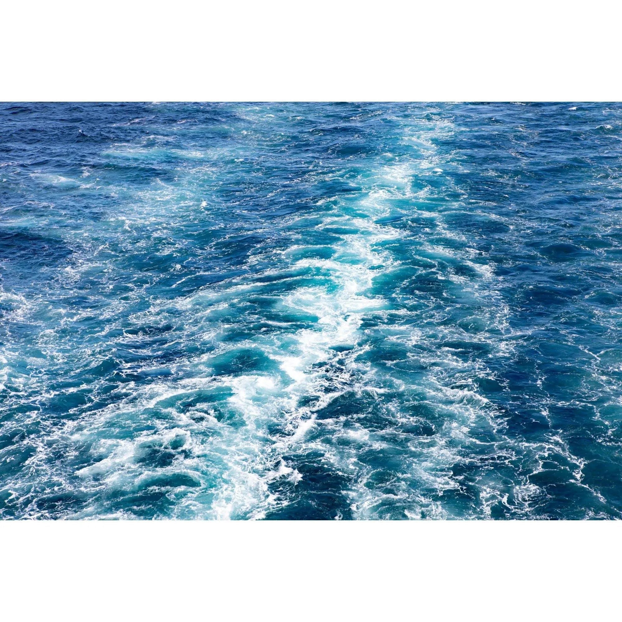 Close-up fine art photograph of swirling blue ocean waves — abstract motion and bright teal highlights.