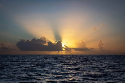 Escape to paradise sunburst of sunset over ocean half hidden behind a cloud