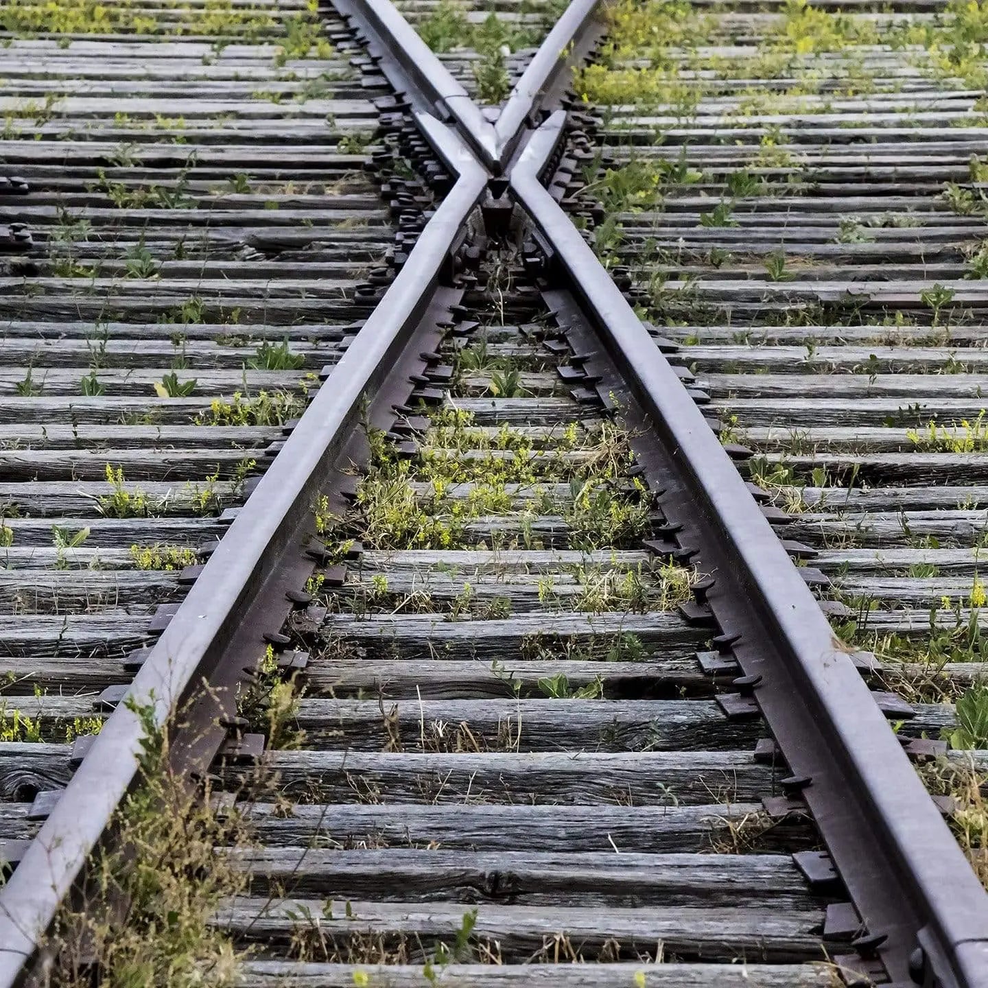 Railroad track fork—minimalist fine-art photograph of diverging rails with gravel texture, industrial black-and-silver tones